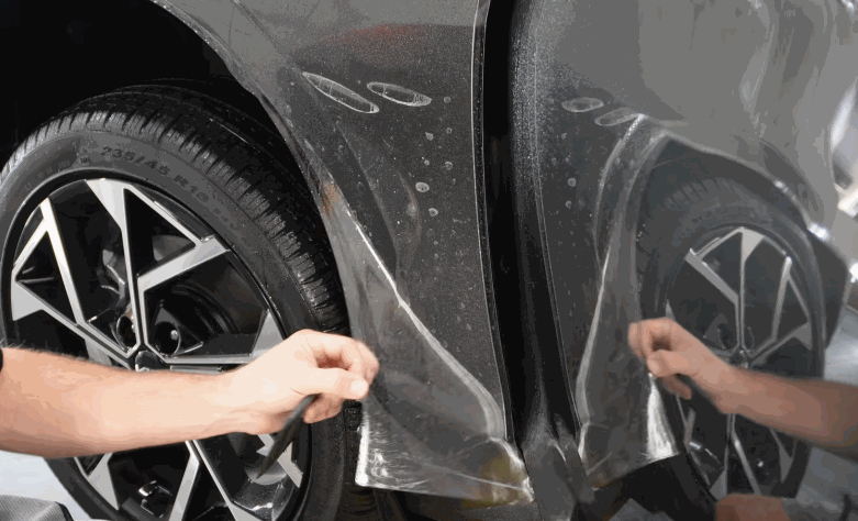 Installer positions paint protection film along the lower side panel near the wheel arch.